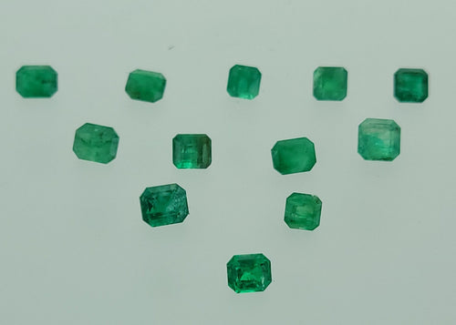 Ten small green rectangular-cut gemstones arranged in a loose triangle on a plain light gray background.