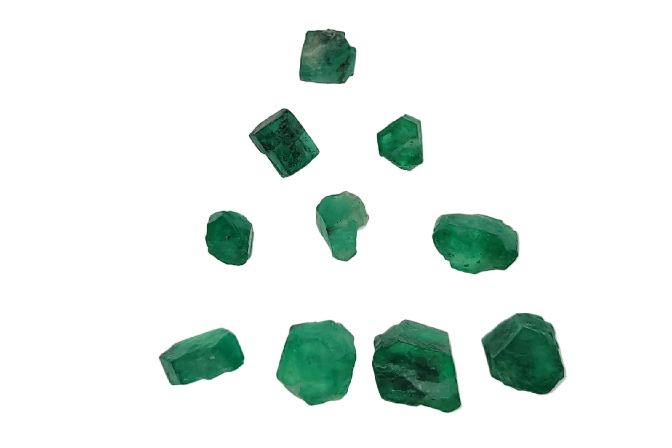 Nine raw green emerald crystals of various sizes arranged in a loose triangle pattern on a plain light gray background.