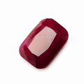 A single rectangular cabochon-cut ruby gemstone with a faceted center, showing a deep red color and a light pink internal reflection, set against a plain white background.