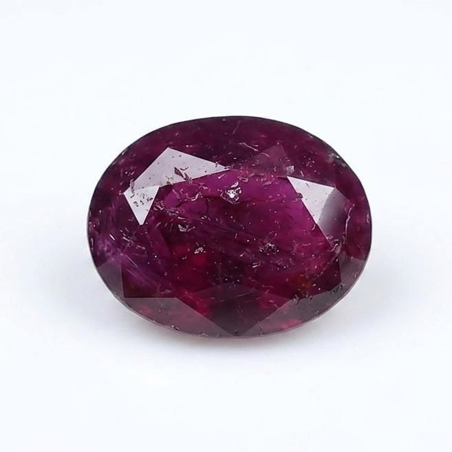 An oval-cut faceted ruby gemstone with deep magenta-pink coloration, displayed on a clean white background.