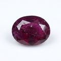 An oval-cut faceted ruby gemstone with deep magenta-pink coloration, displayed on a clean white background.