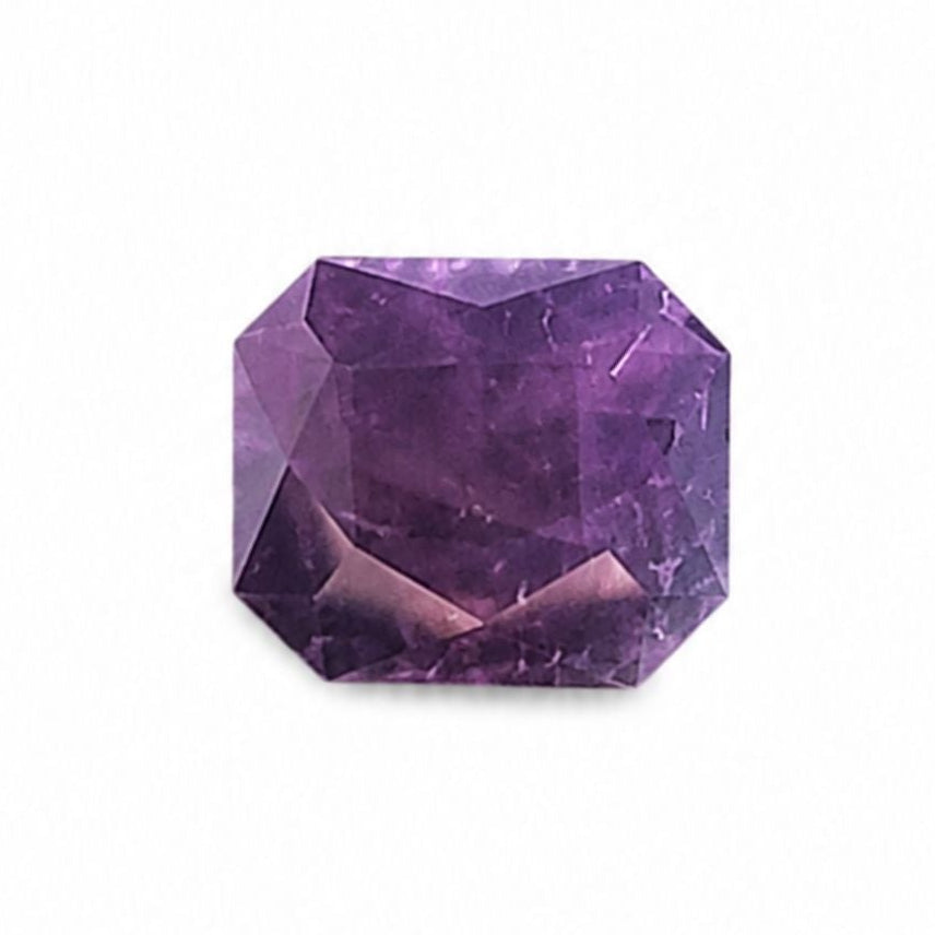 A faceted purple gemstone, cut in a square or octagonal shape, shown on a plain white background.